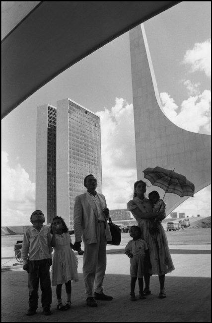 BRAZIL. Brasilia. 1960. Worker from Nordeste shows his family the new city on inauguration day. In the background: the National Congress building by Oscar NIEMEYER.